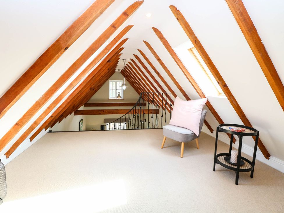 A loft with wooden beams and an armchair at Horseshoe Stable, Mattishall