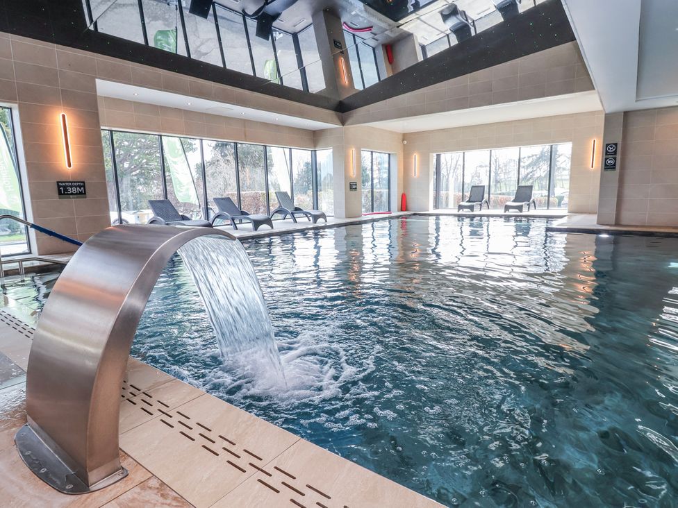 An indoor pool area with lounge chairs and glass windows at Woodlands Gold (WO 41) Ruthin
