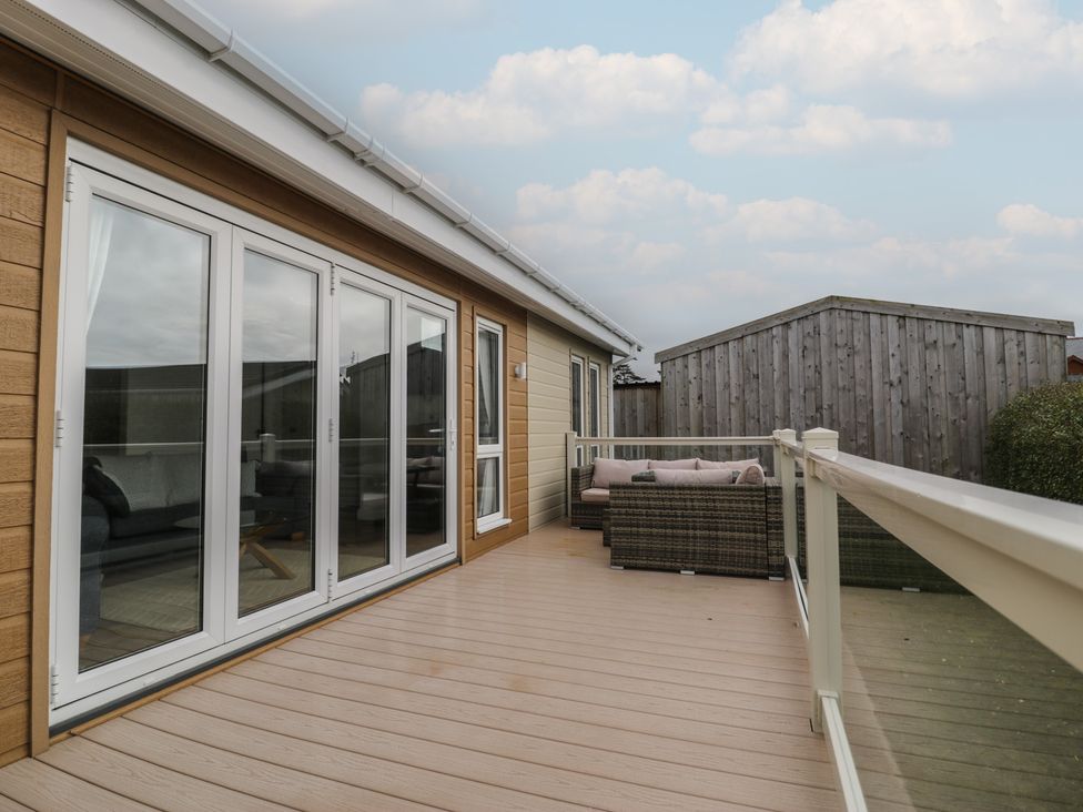 A deck area with sliding doors and outdoor furniture at Platinum Lodge (503) Talybont