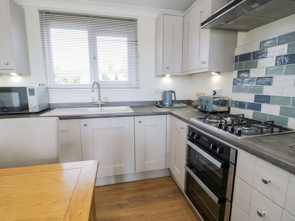 A kitchen with appliances including a microwave, sink, and gas stove at Platinum Lodge (503) Talybont