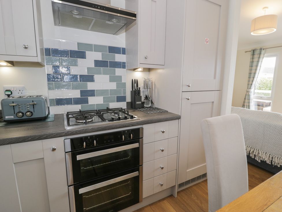 A kitchen with cabinets and a gas stove at Platinum Lodge (503) Talybont