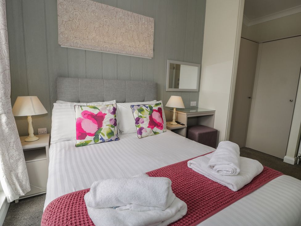 A bedroom with a bed, pillows, a lamp, and a mirror at Platinum Lodge (503) Talybont