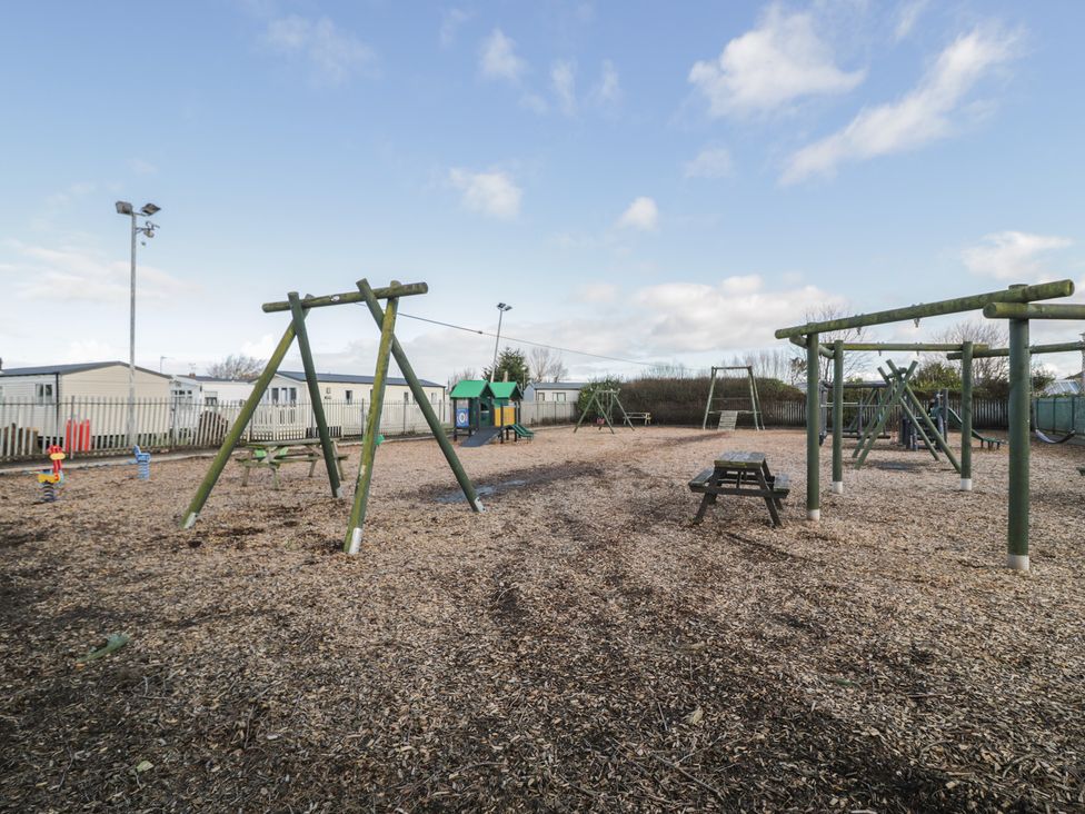 A playground with swings and play equipment at Lido Silver Plus 111 Prestatyn