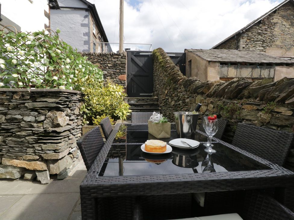 An outdoor dining area with table and cake at Nutkin Cottage in Windermere