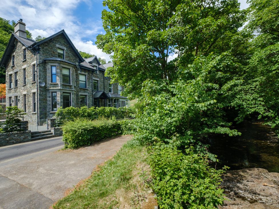 A stone house with trees and bushes near a stream at Riverside in Ambleside