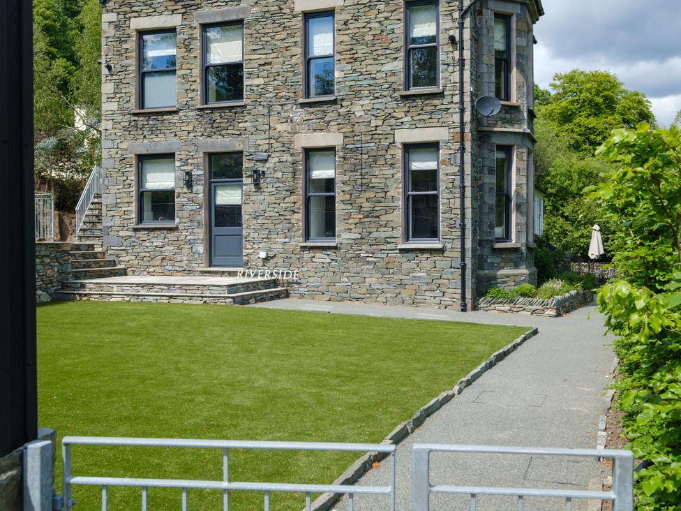 A stone house with a lawn and pathway at Riverside in Ambleside