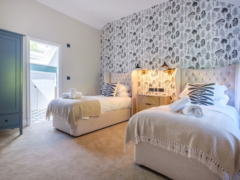 A bedroom with two beds and a wardrobe at Riverside in Ambleside