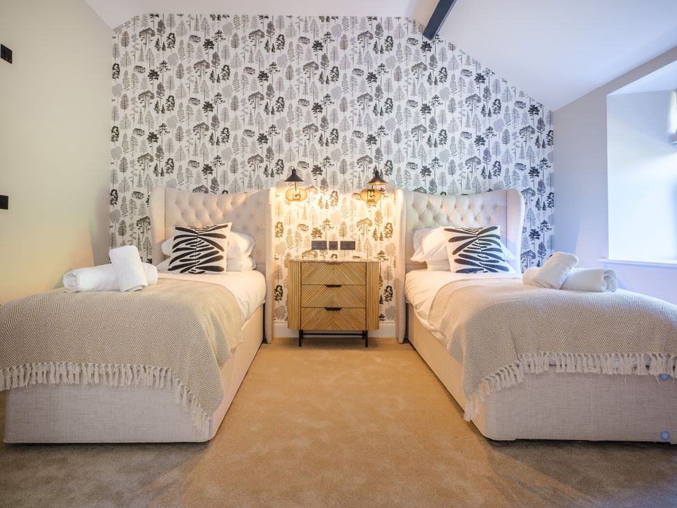 A bedroom with two beds and a nightstand at Riverside in Ambleside