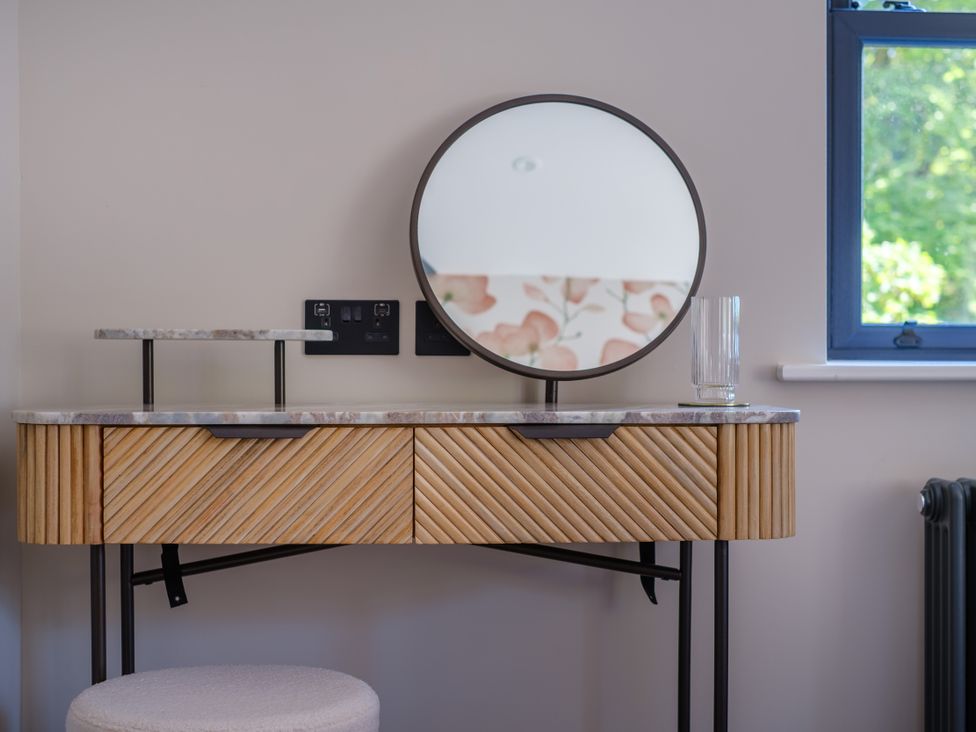 A vanity table with a round mirror at Riverside in Ambleside