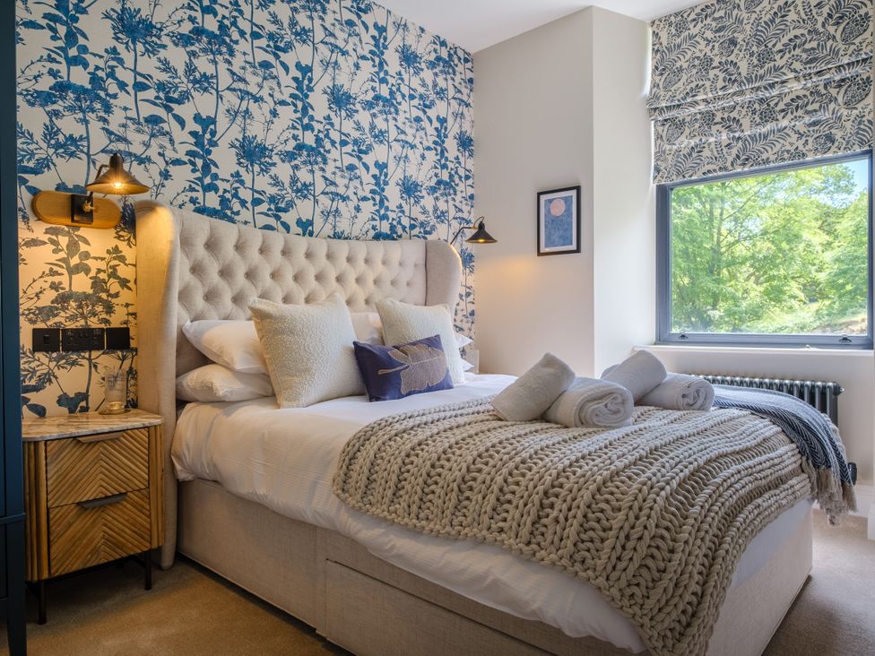 A bedroom with a bed, nightstand, and window at Riverside in Ambleside