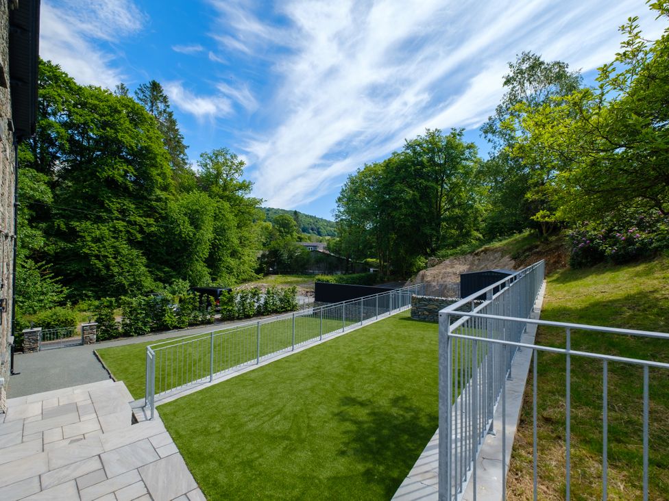 A garden with grass and a fence at Riverside in Ambleside