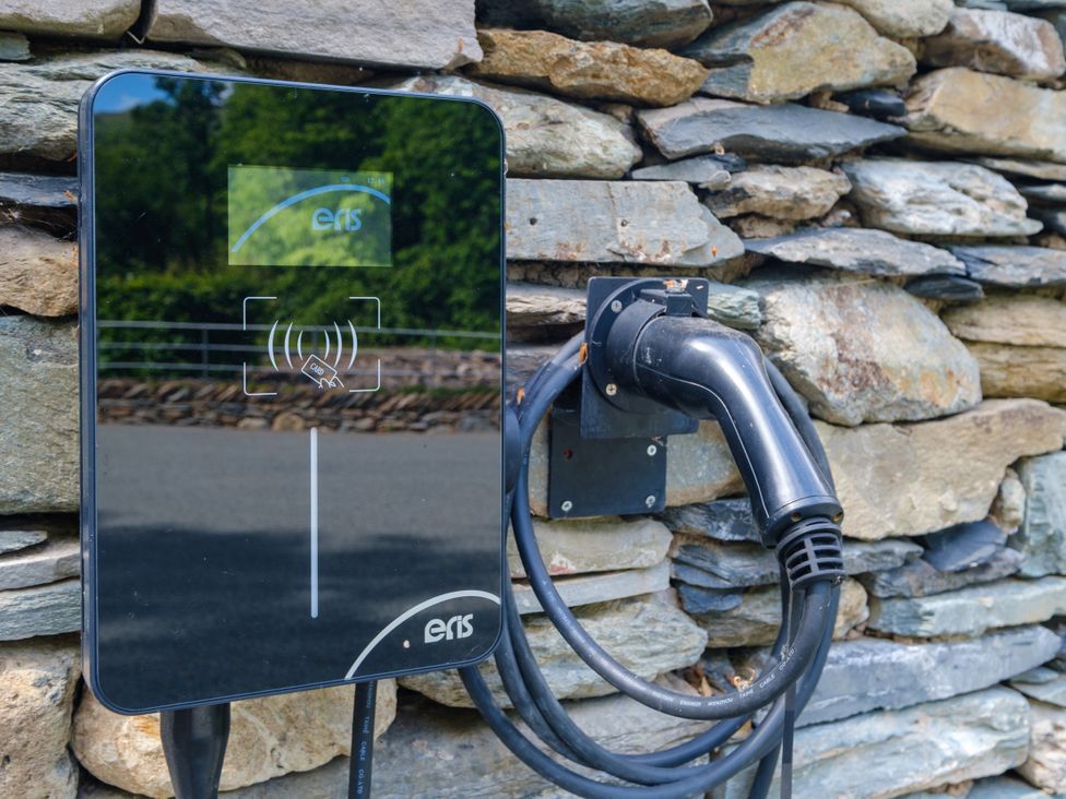 An electric vehicle charger mounted on a stone wall at Riverside in Ambleside