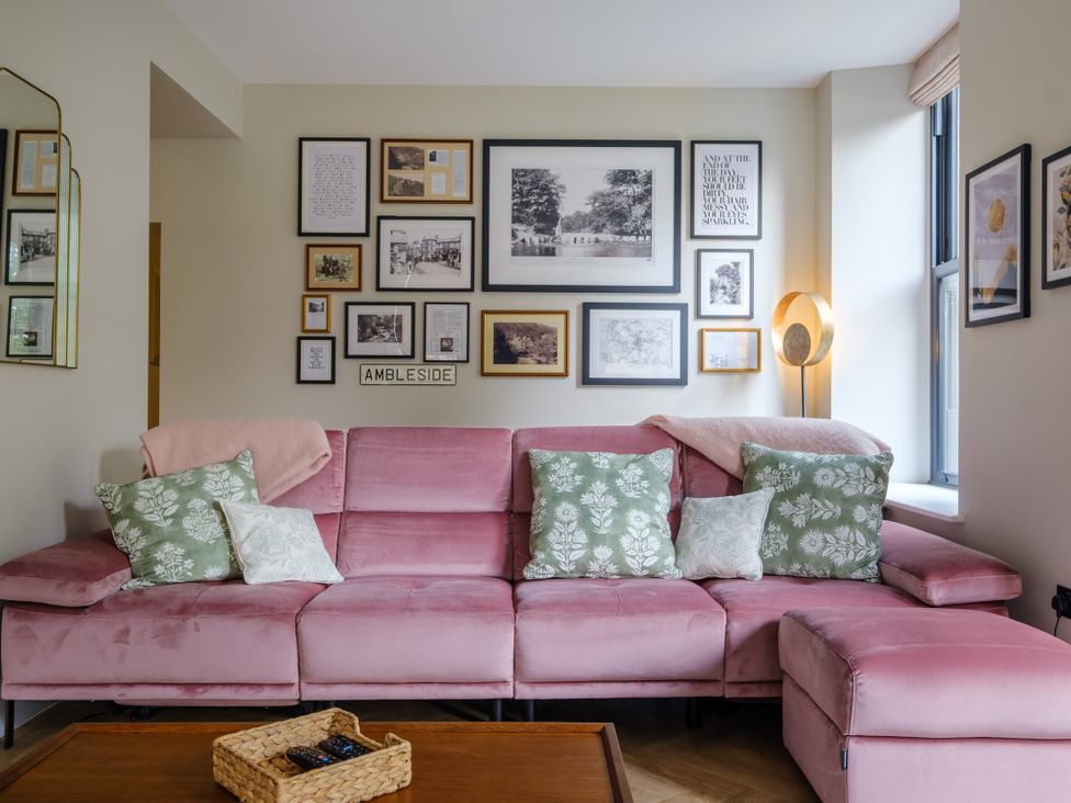 A living room with a pink sofa and framed pictures at Riverside in Ambleside