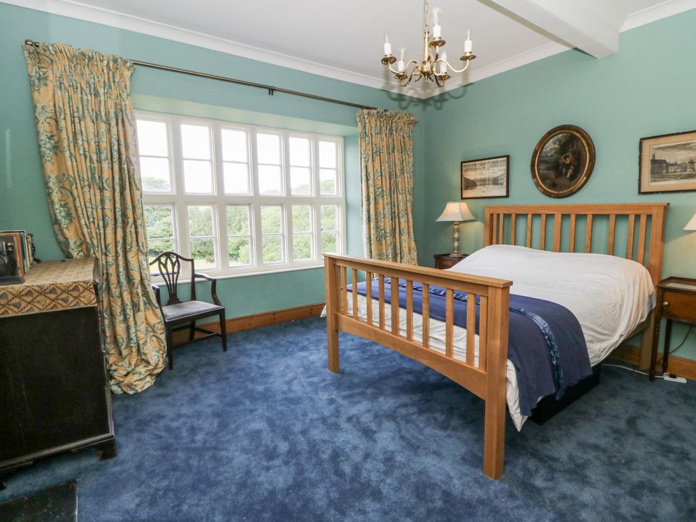 A bedroom with a bed, chair, and window at Plas Pontfaen near Fishguard and Newport, Pembrokeshire