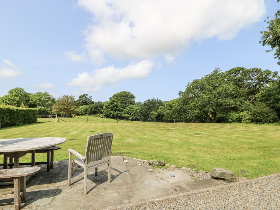 A garden with a table and chair overlooking a grassy area at Plas Pontfaen near Fishguard and Newport, Pembrokeshire