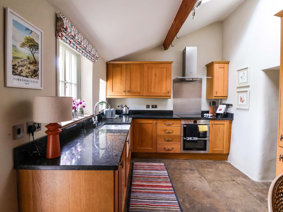 A kitchen with wooden cabinets and appliances at Ellis House in Skipton
