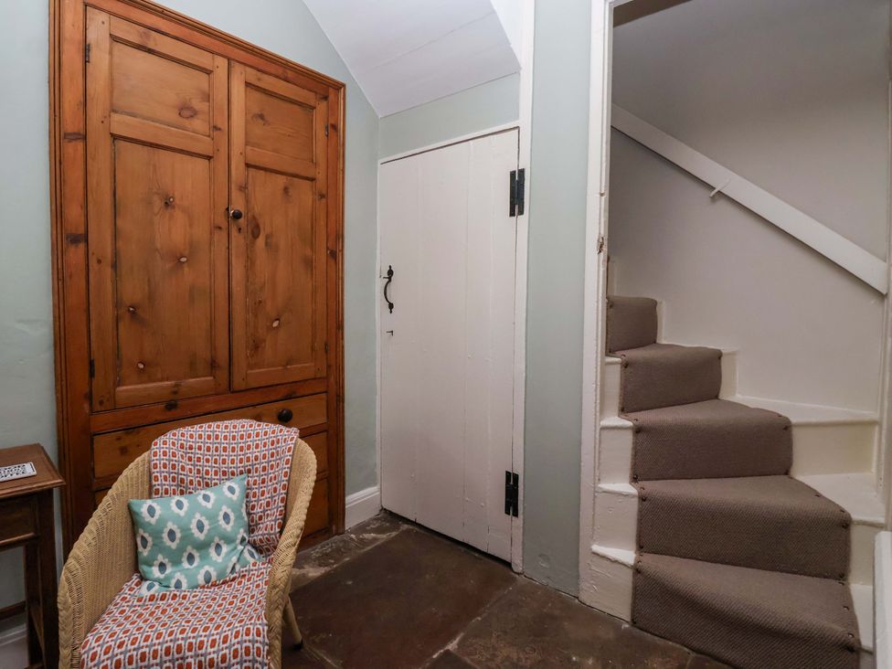 A hallway with a wardrobe, chair, and stairs at Ellis House in Skipton
