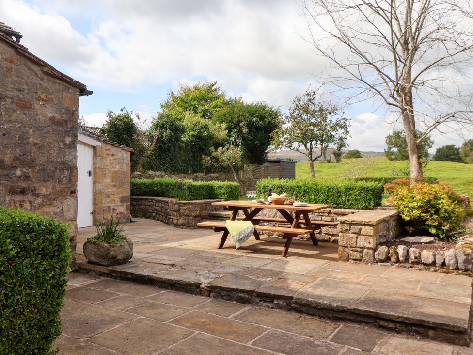 A garden with a table and benches at Ellis House in Skipton