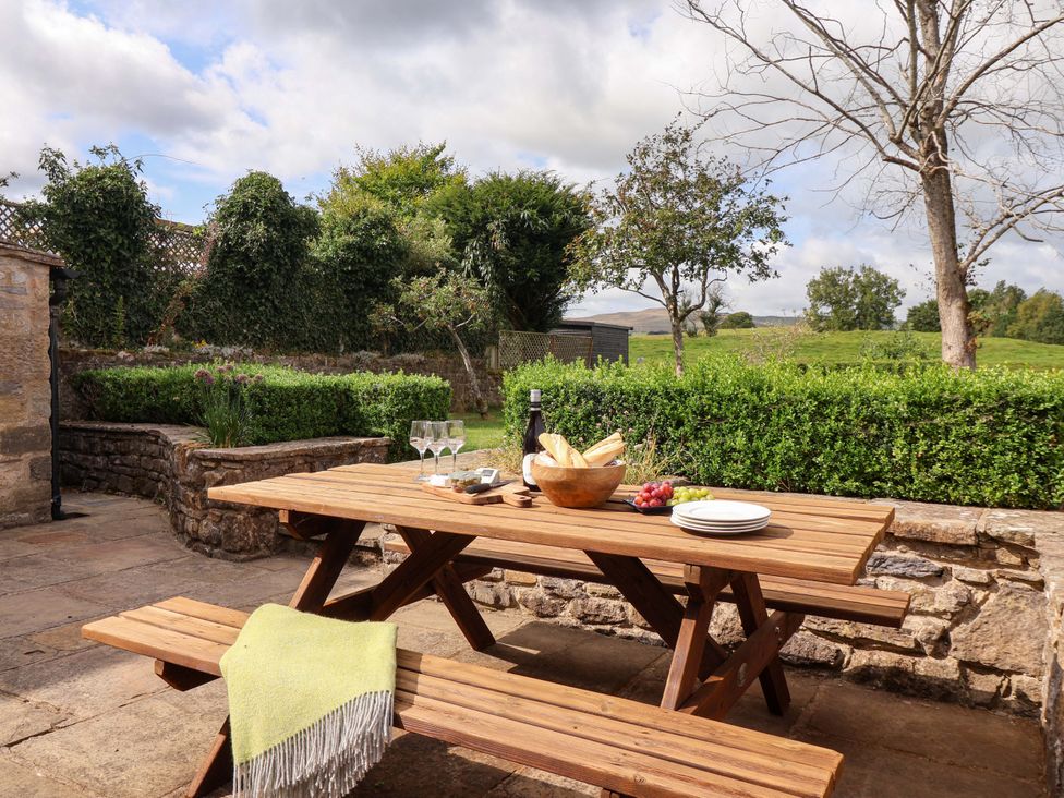 An outdoor dining area with a wooden table and benches at Ellis House in Skipton
