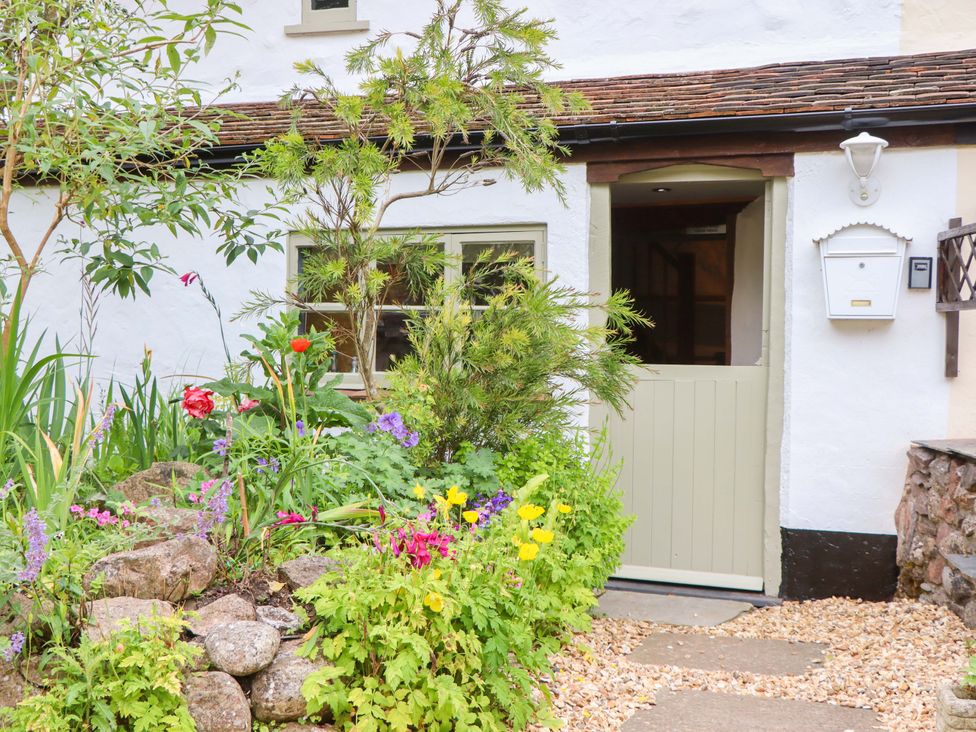 A garden with a door and flowers at 1 Myrtle Cottages Stokeinteignhead