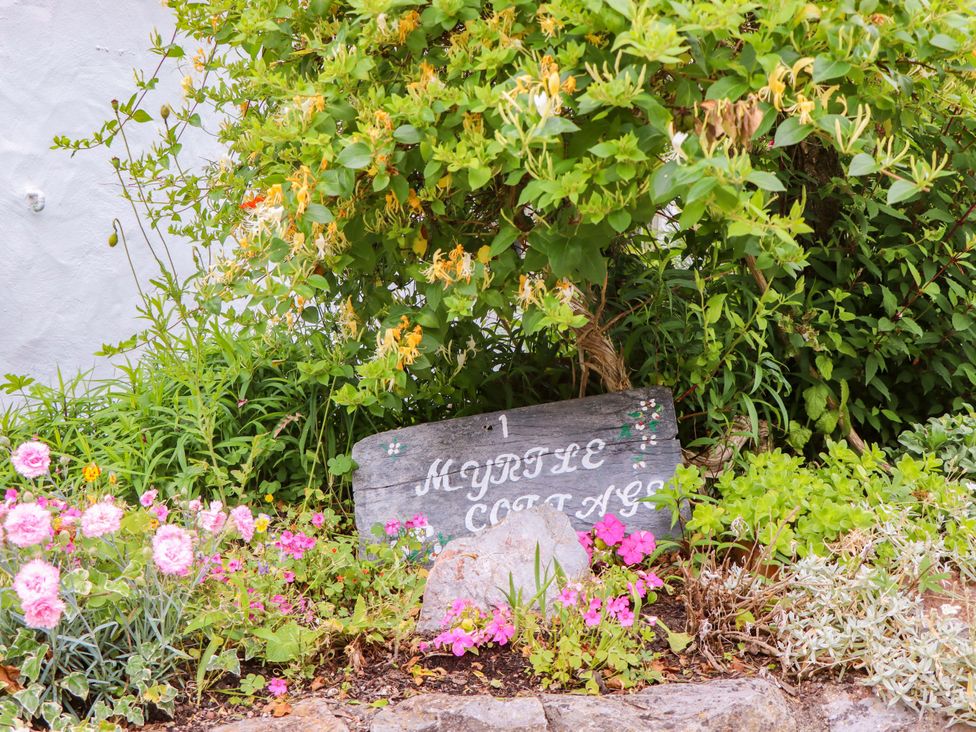 A garden with a sign and flowers at 1 Myrtle Cottages Stokeinteignhead