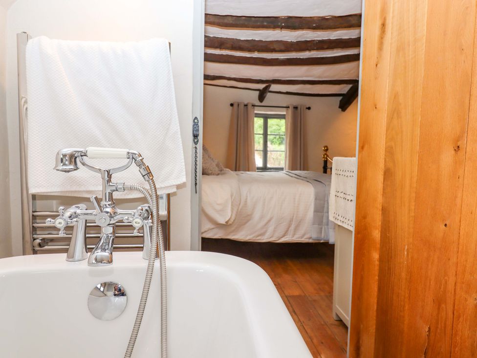 A bathroom featuring a bathtub and a view of a bedroom at 1 Myrtle Cottages Stokeinteignhead