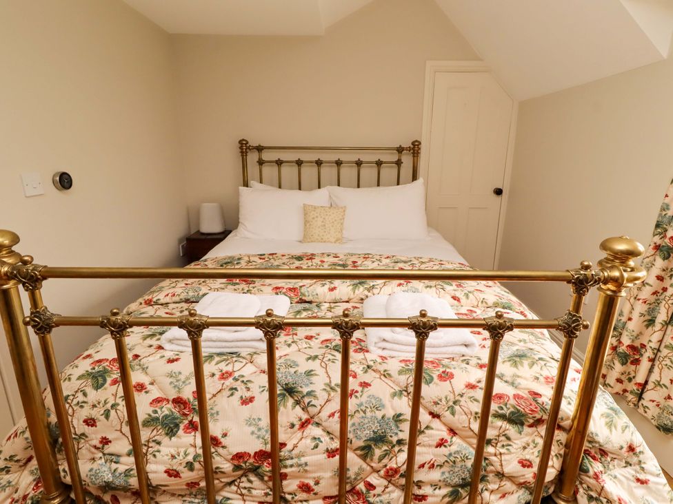 A bedroom with a brass bed and floral bedding at 9 Longhirst Village Morpeth