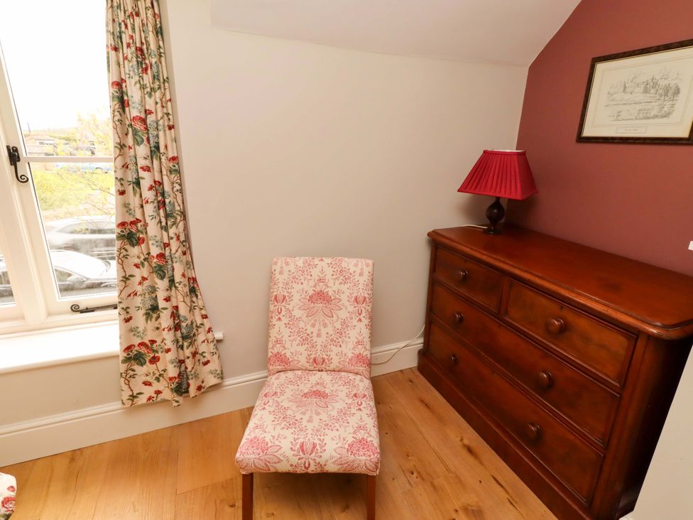 A bedroom with a chair and dresser at 9 Longhirst Village in Morpeth