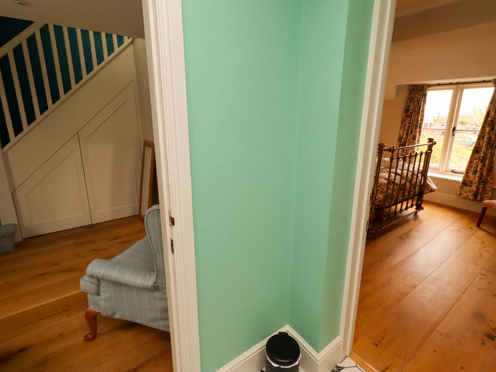A hallway with a staircase and an armchair at 9 Longhirst Village, Morpeth
