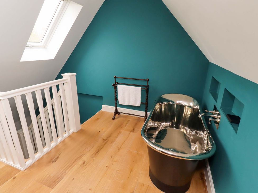 A bathroom with a bathtub and towel rack at 9 Longhirst Village in Morpeth