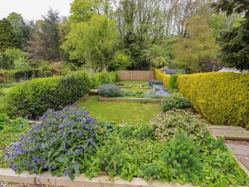 A garden with flowerbeds and a hedge at 9 Longhirst Village, Morpeth