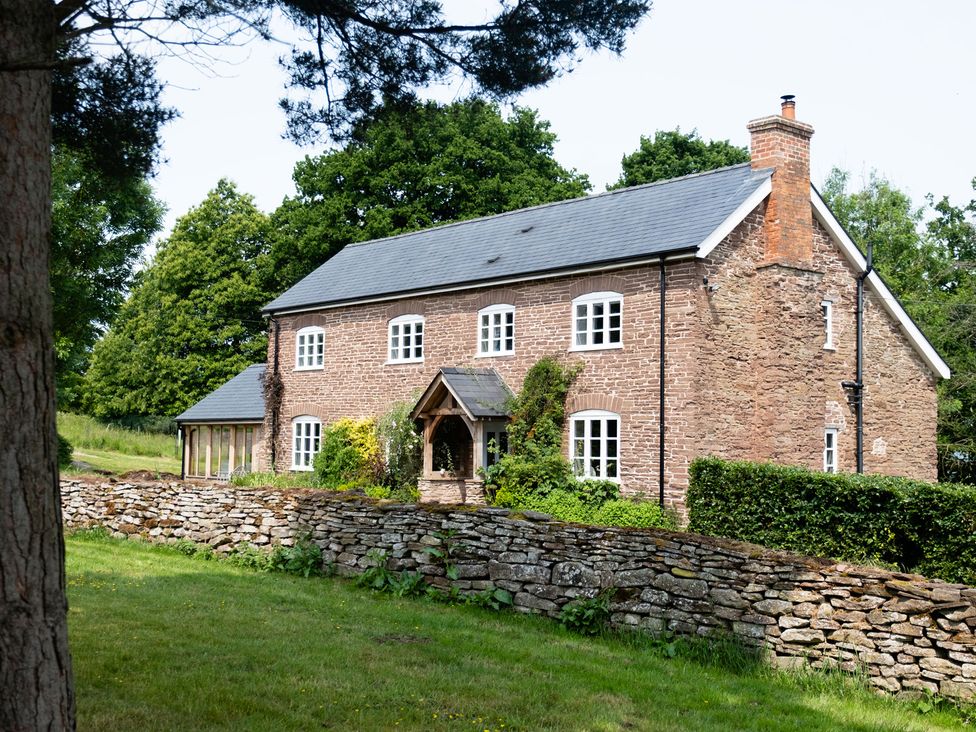 A house with a stone wall and trees at Henhouse Farm in Bodenham