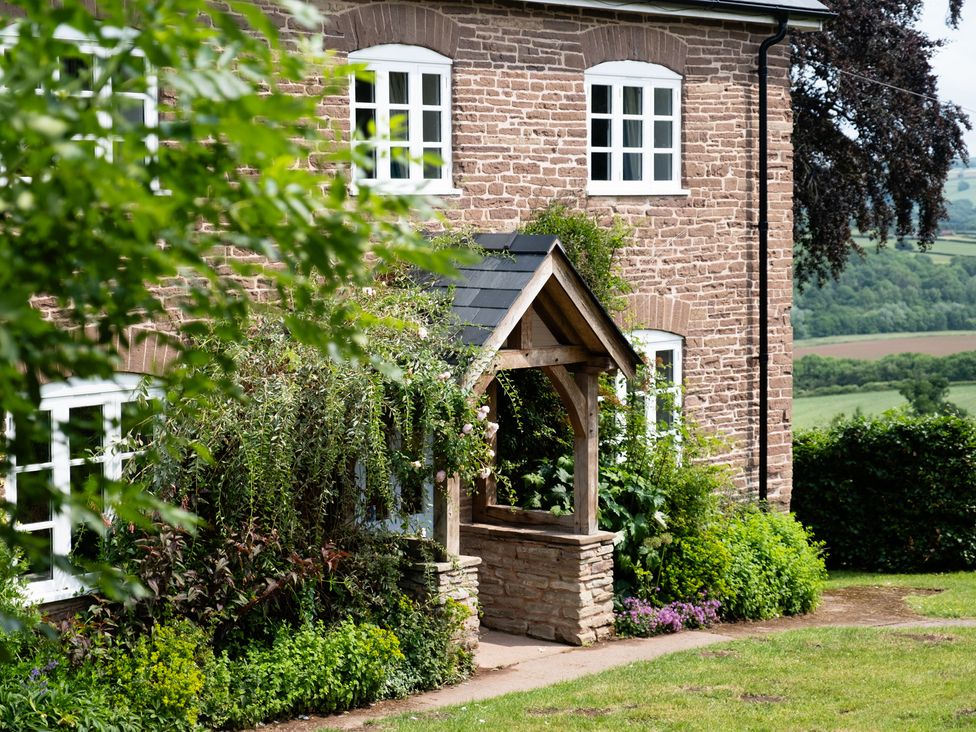 An outdoor view of a house with a garden and pathway at Henhouse Farm in Bodenham