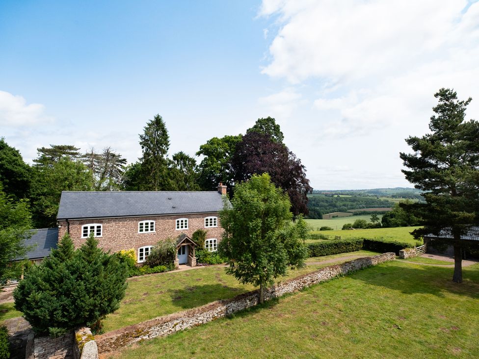 An exterior view of a house with trees and a garden at Henhouse Farm in Bodenham