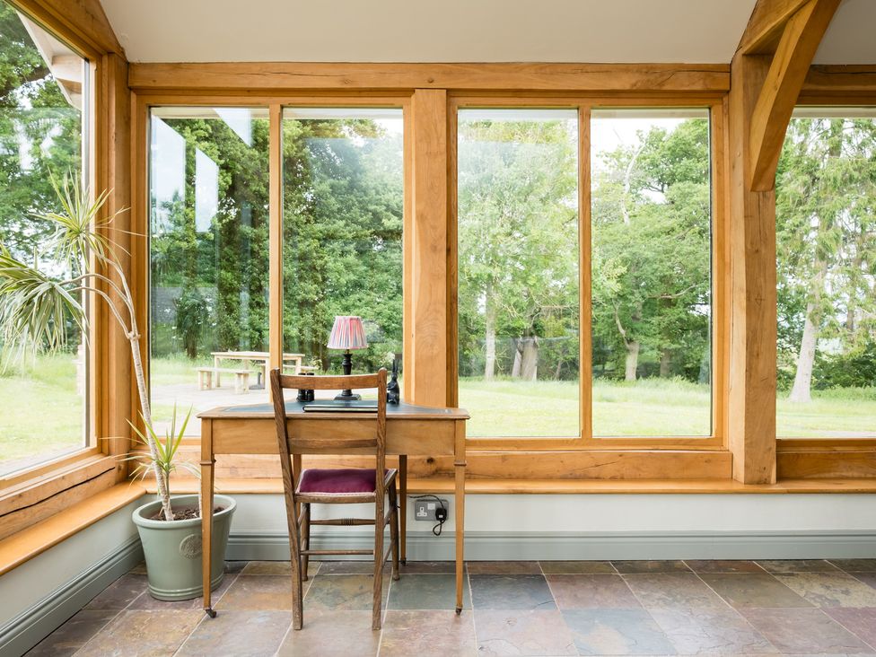A conservatory with a desk and chair at Henhouse Farm in Bodenham