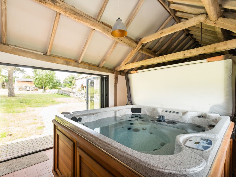 A hot tub in a room with wooden beams at Henhouse Farm in Bodenham