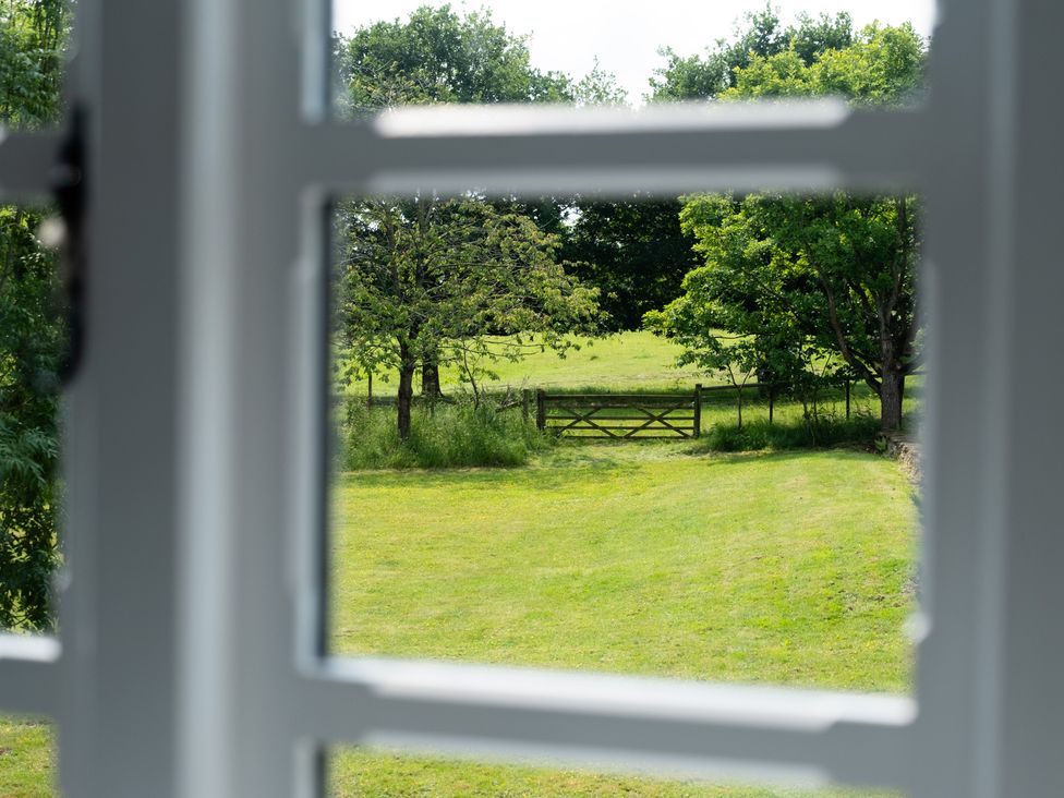 An outdoor view showing trees and a gate from a window at Henhouse Farm Bodenham