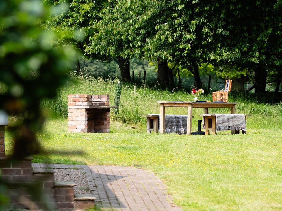 A garden with a barbecue grill and a table set with flowers at Henhouse Farm in Bodenham