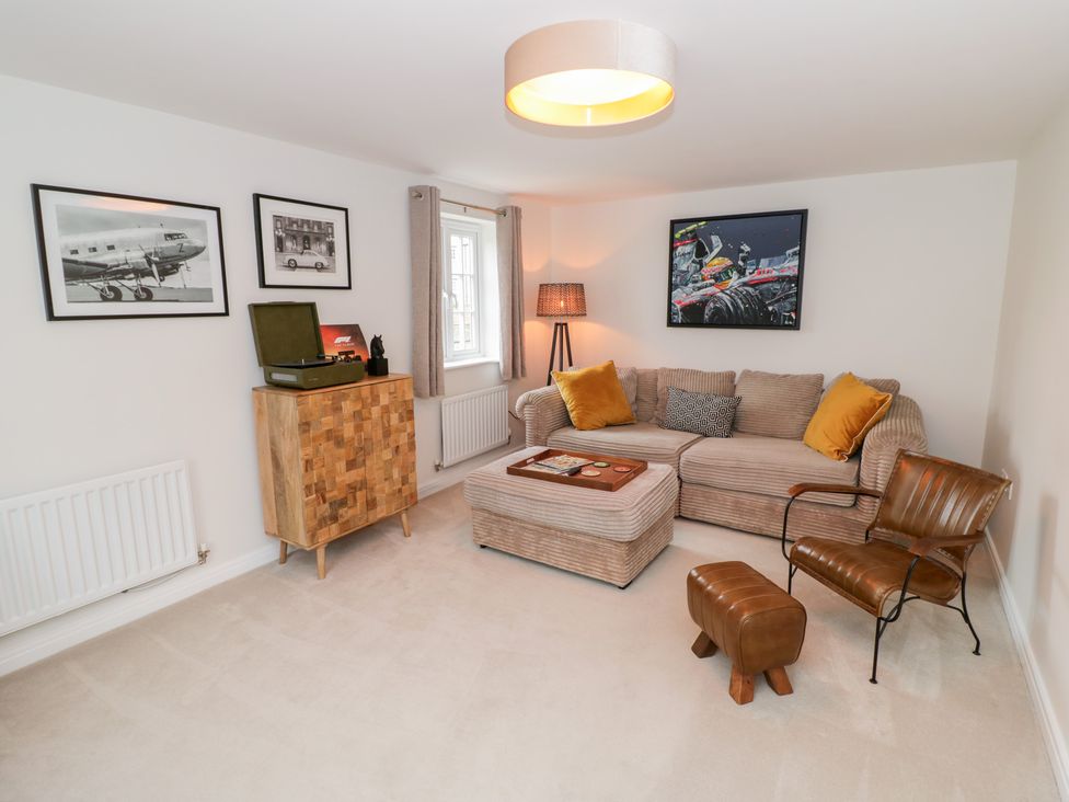 A living room with a sofa and armchair at Silverstone Paddock Retreat in Silverstone