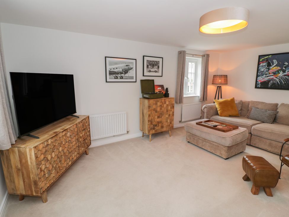 A living room with a television and sofa at Silverstone Paddock Retreat in Silverstone