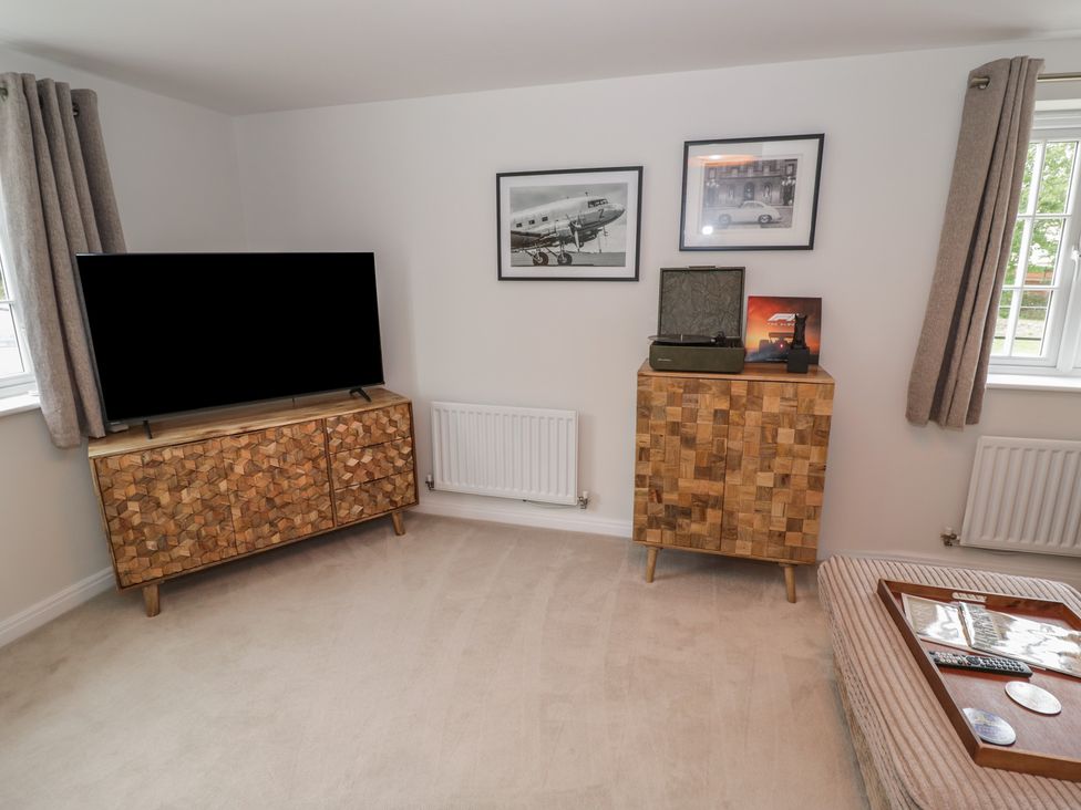 A living room with a television and wooden cabinet at Silverstone Paddock Retreat in Silverstone