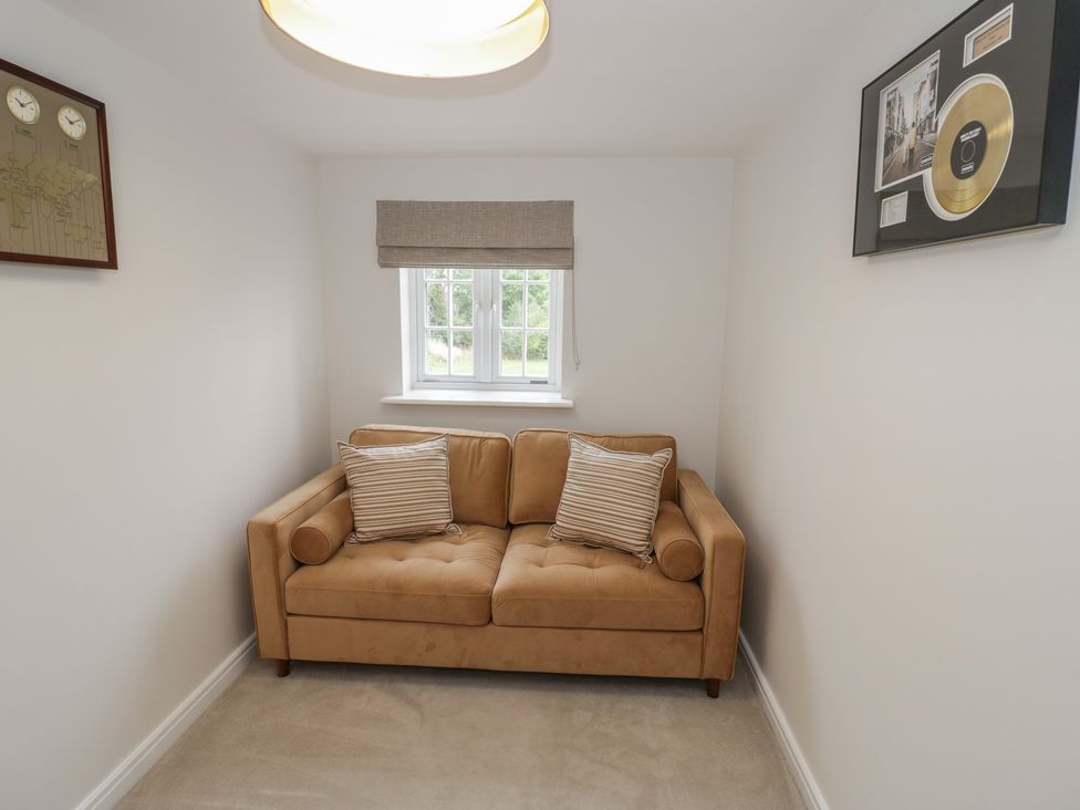 A snug room with a sofa and window at Silverstone Paddock Retreat in Silverstone