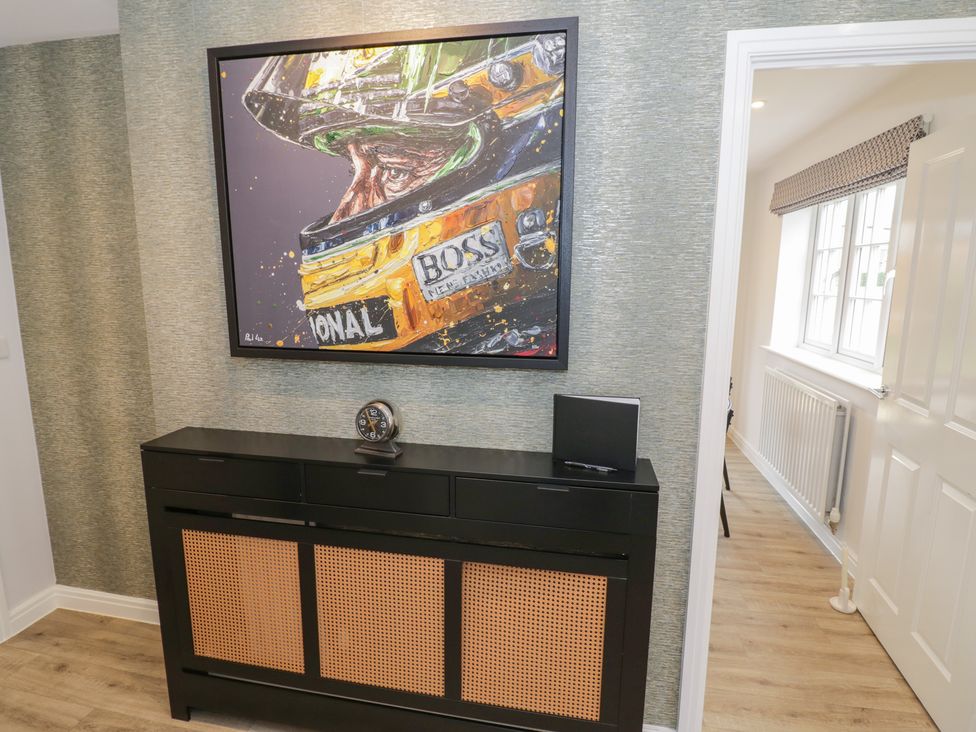 A hallway with a console table and artwork at Silverstone Paddock Retreat in Silverstone