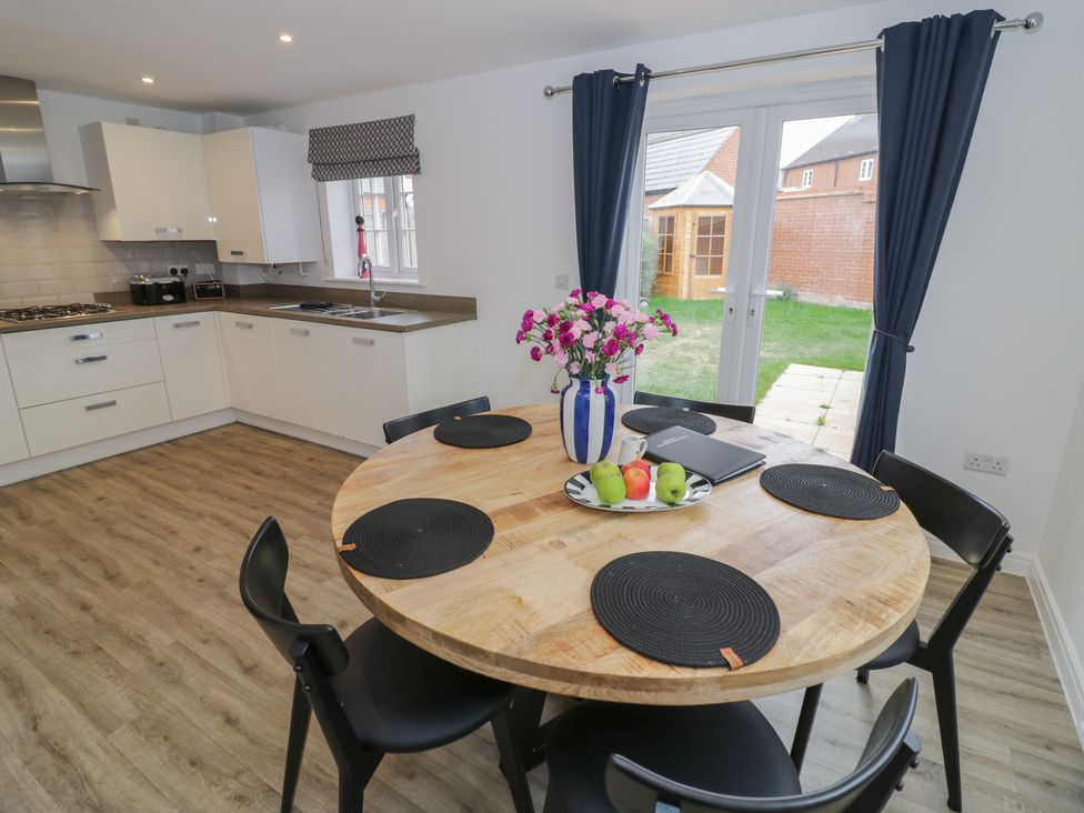A kitchen with a round dining table and chairs at Silverstone Paddock Retreat in Silverstone