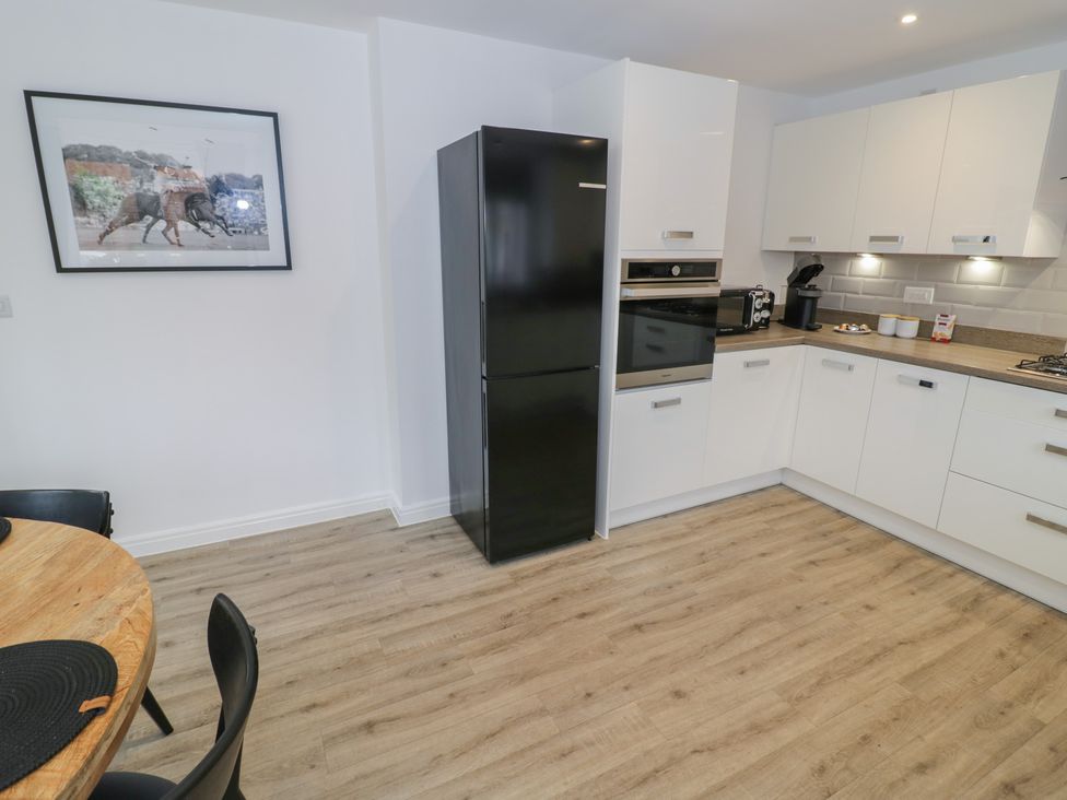 A kitchen with appliances and a dining table at Silverstone Paddock Retreat in Silverstone