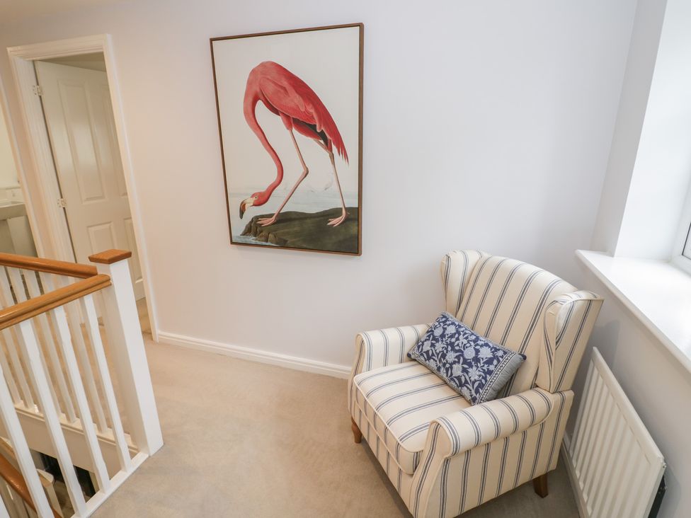 A landing with an armchair and a flamingo painting at Silverstone Paddock Retreat in Silverstone