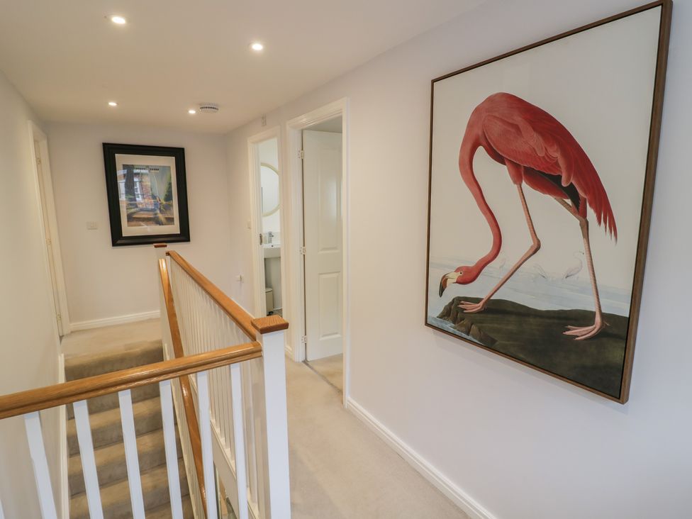 A hallway with stairs and a flamingo painting at Silverstone Paddock Retreat in Silverstone