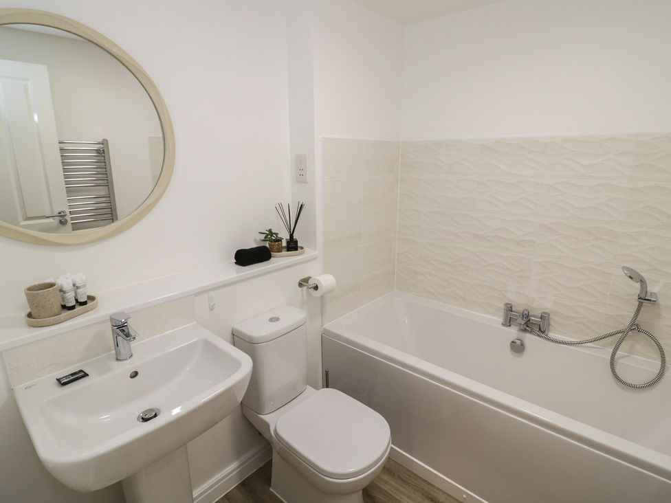 A bathroom with a sink, toilet, and bath tub at Silverstone Paddock Retreat in Silverstone