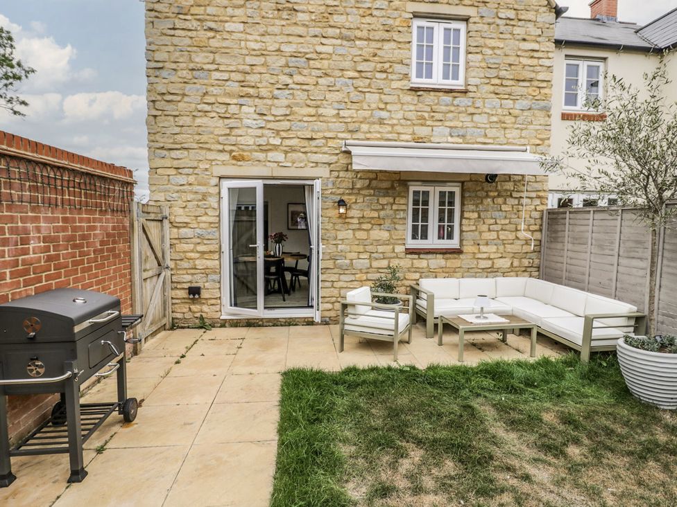 A garden with a seating area and grill at Silverstone Paddock Retreat in Silverstone