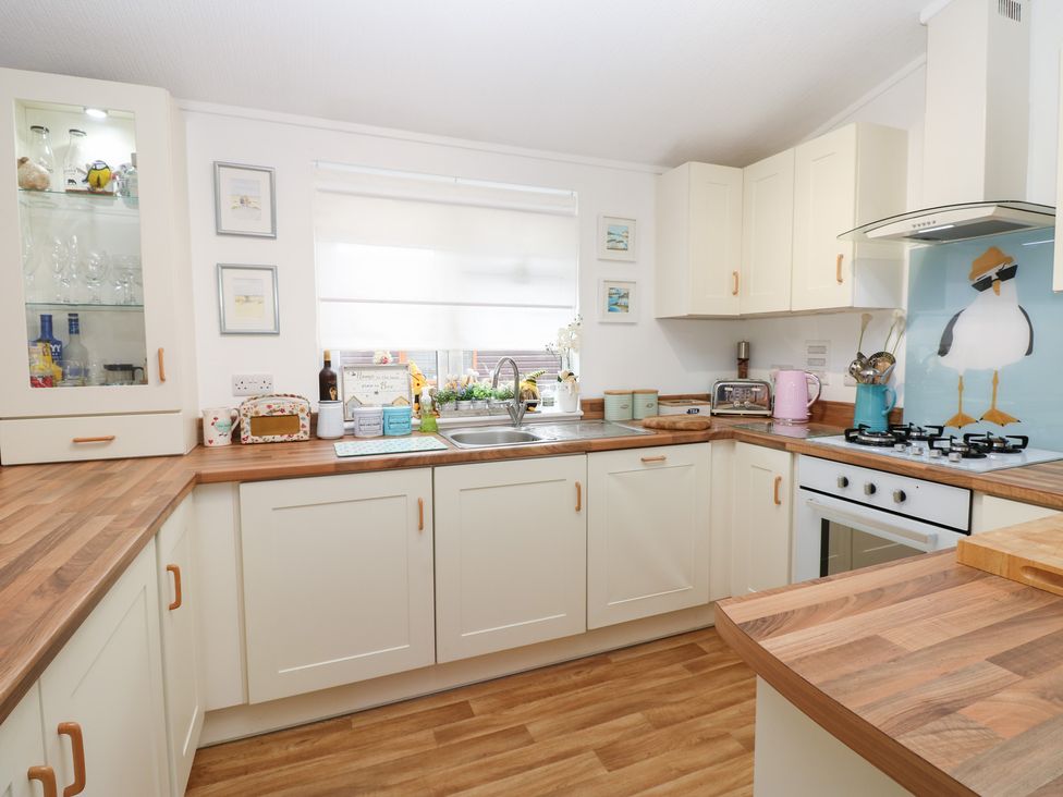 A kitchen with cabinets, sink, stove, and various appliances at The Sanctuary Badgers Retreat Holiday Park near Catterick Garrison, North Yorkshire